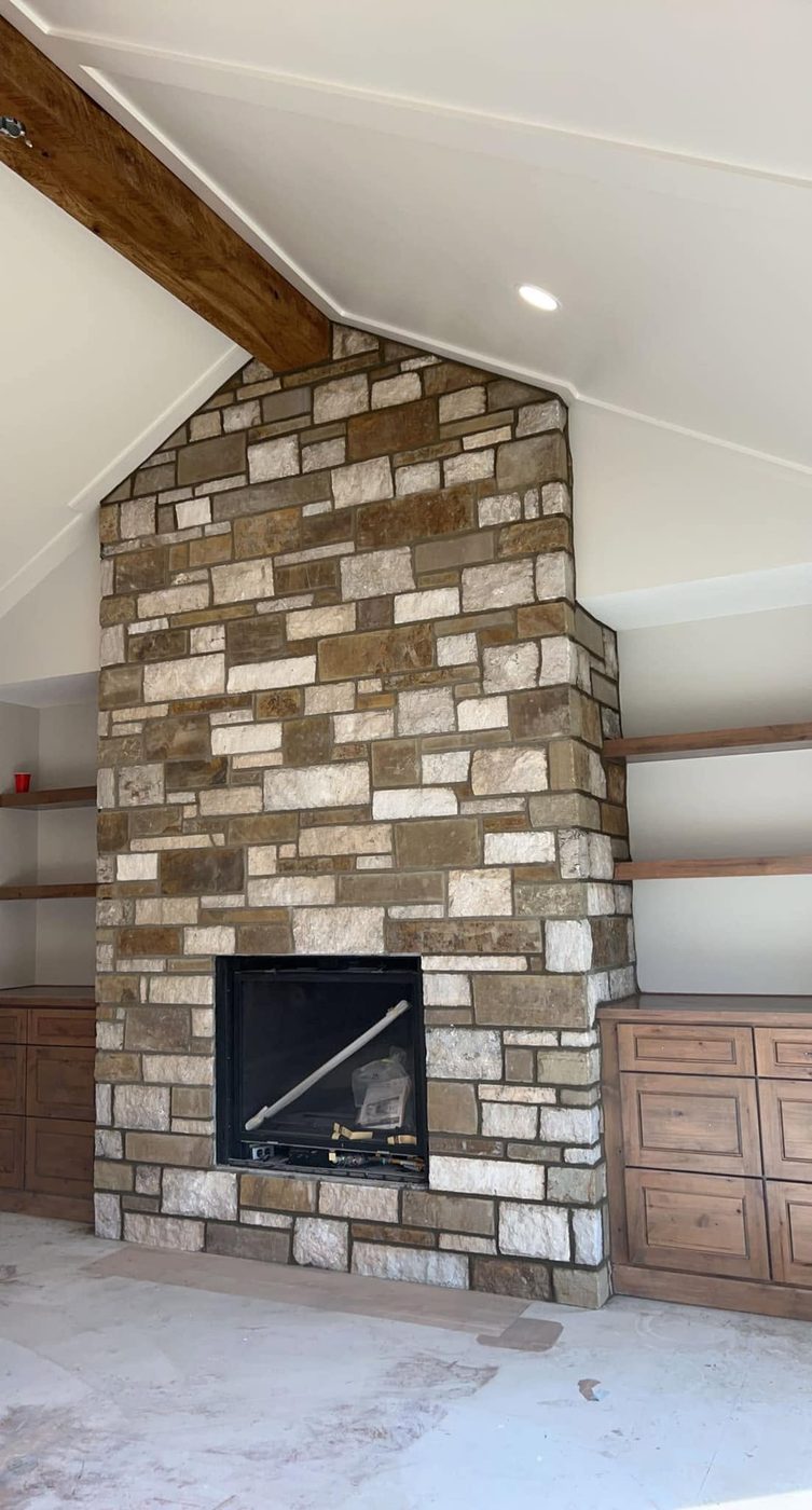 Covered porch fireplace in mixed cream and brown stone with built-ins