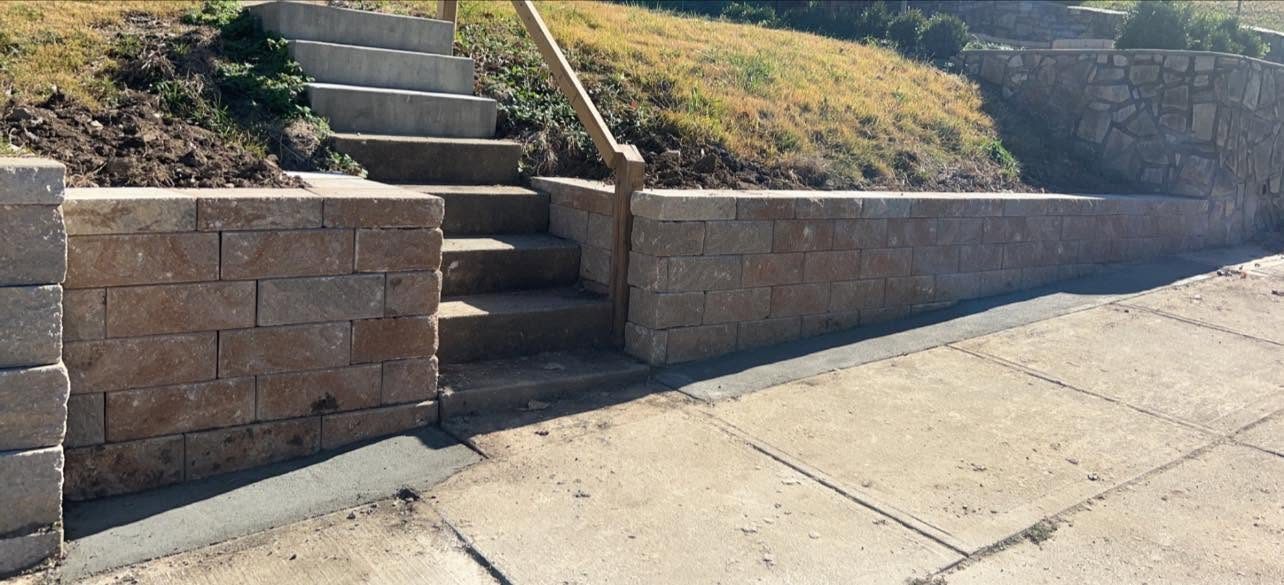 New block retaining wall with steps and handrail along the sidewalk