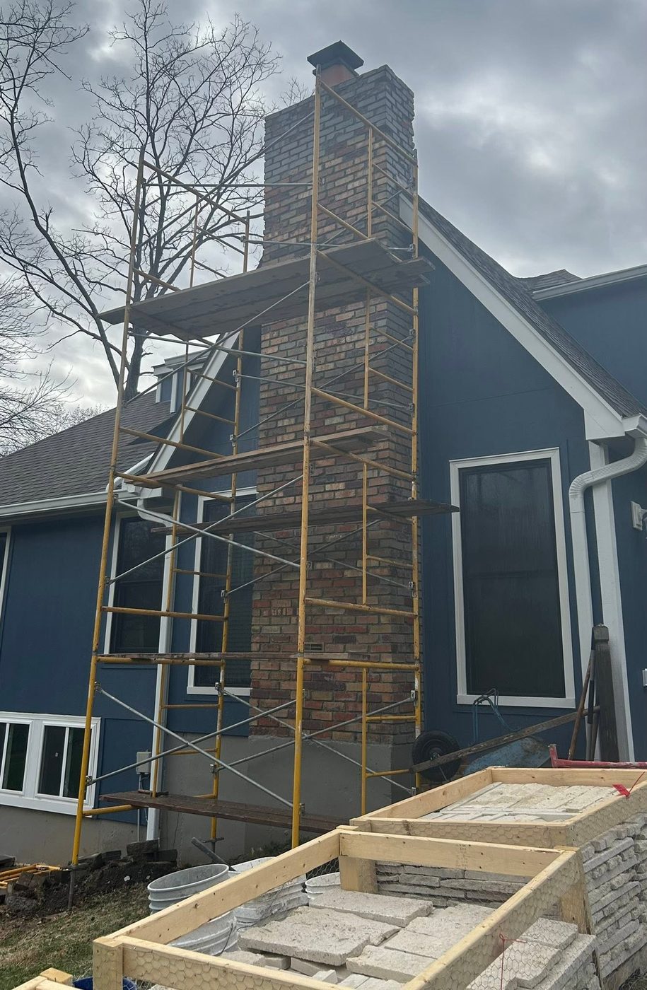 Original brick chimney on the blue house, scaffolded before stone refacing