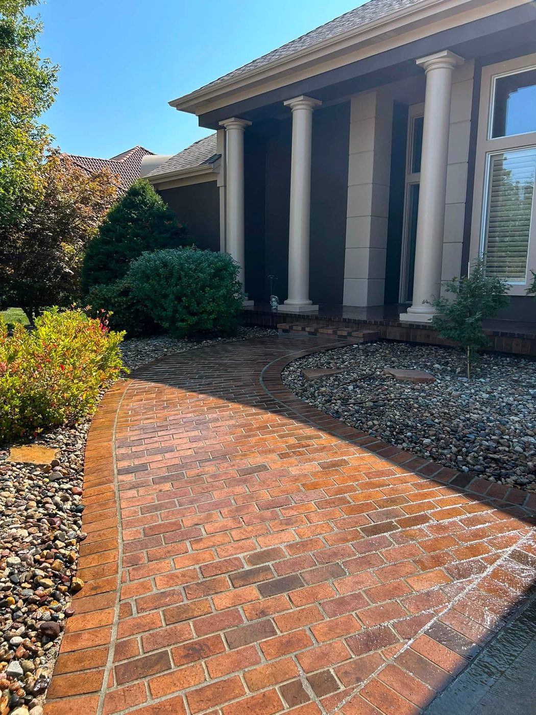 Curving brick paver walkway beside a columned porch