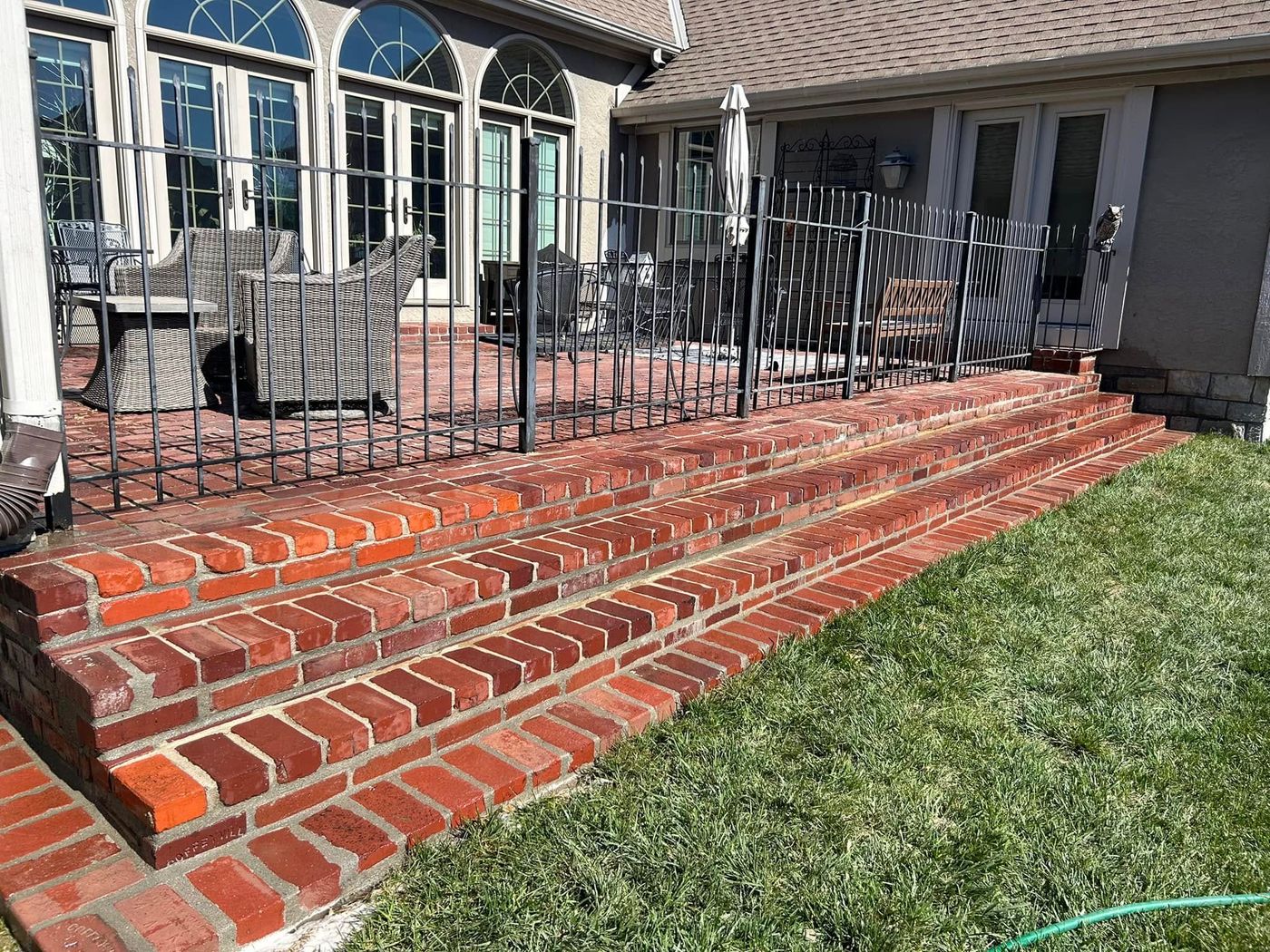 Wide brick steps up to a fenced patio