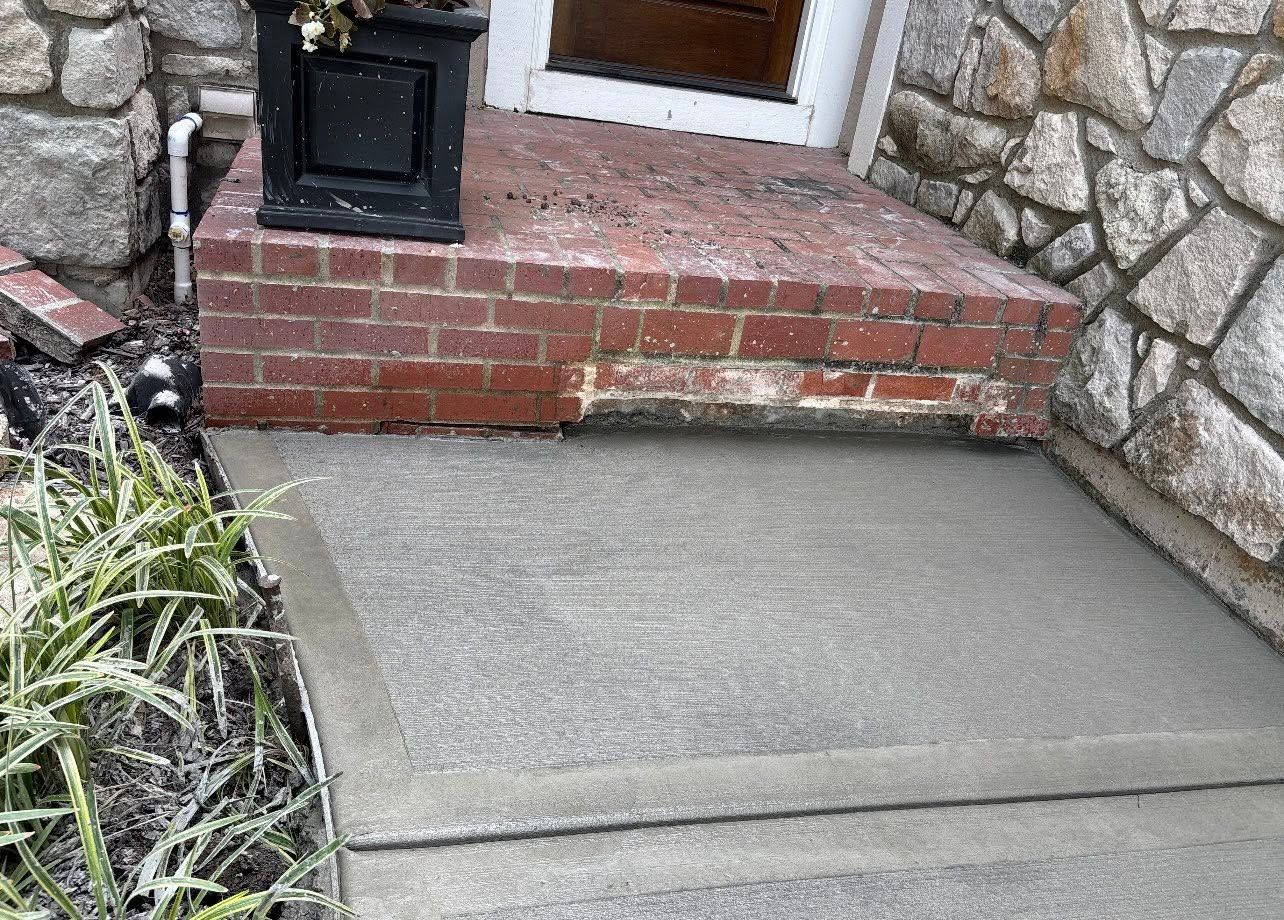 Worn brick step with a new concrete pad