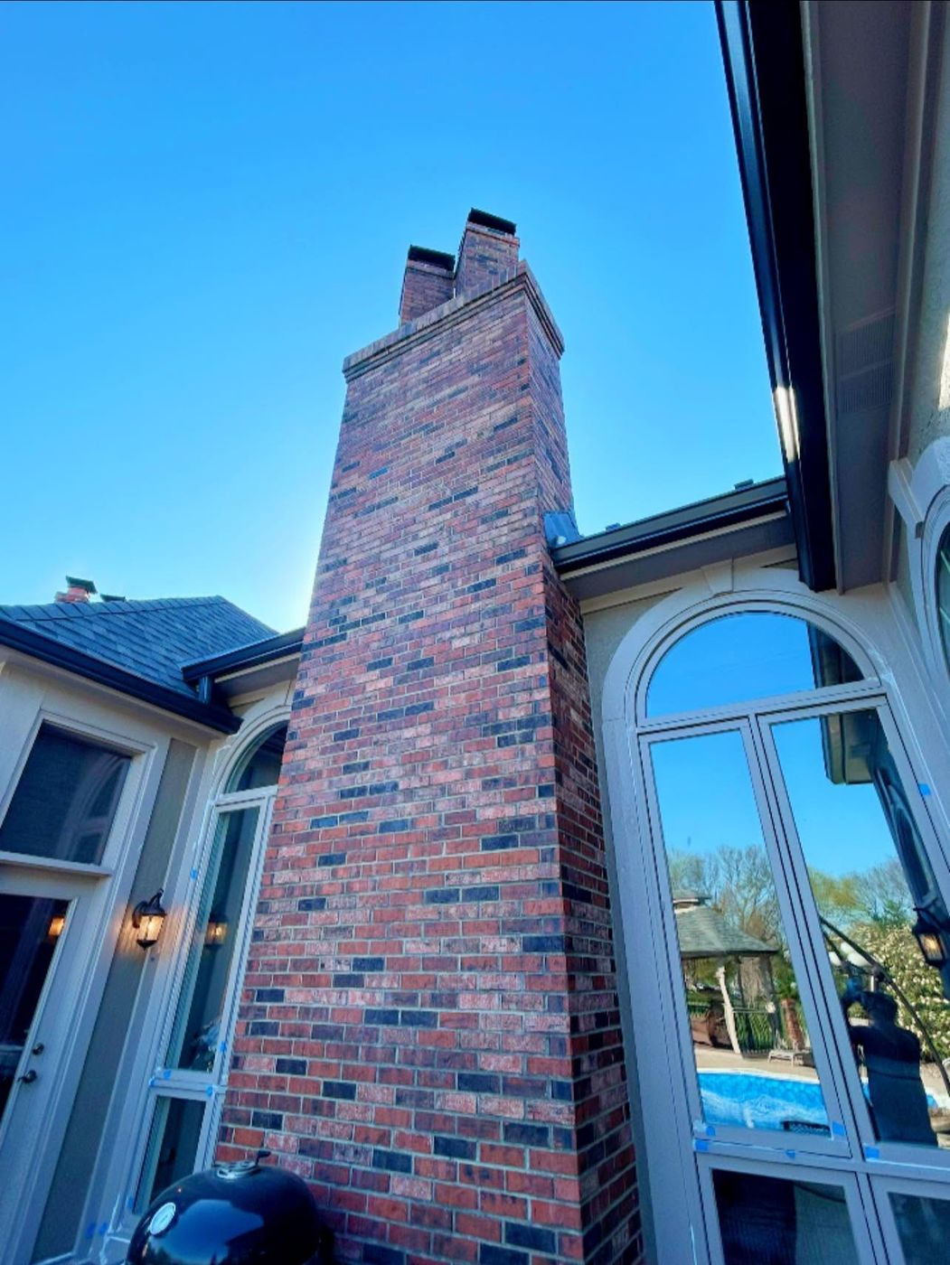 Tall red brick chimney beside arched windows