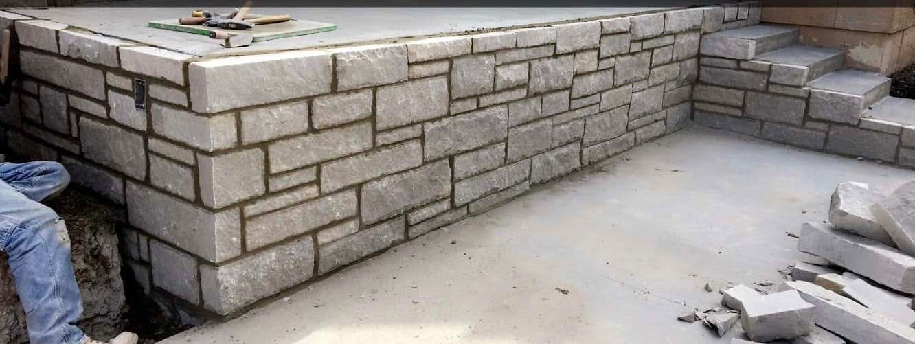 Light cut stone wall being set in a coursed pattern
