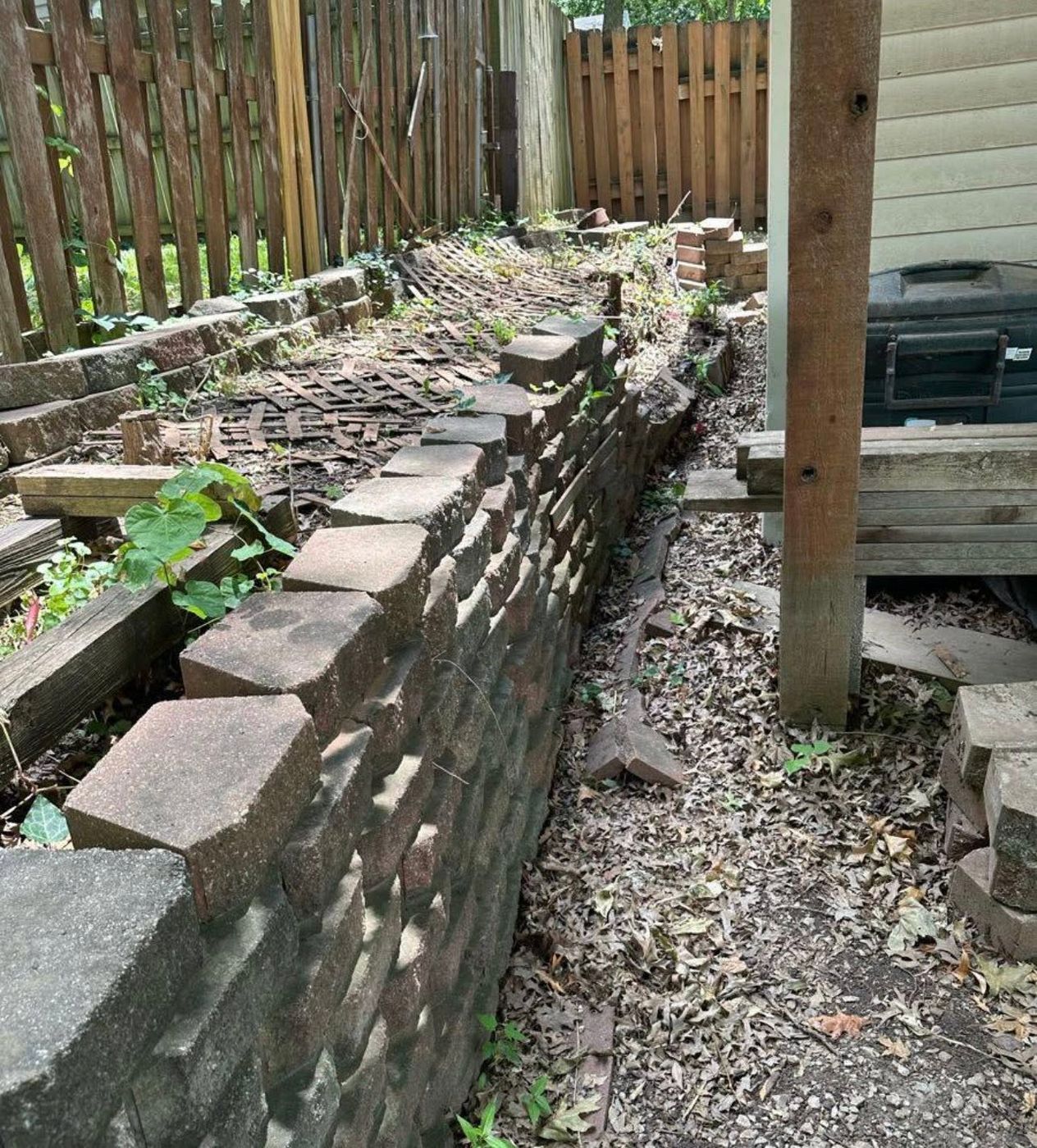 Old, overgrown garden wall along a fence