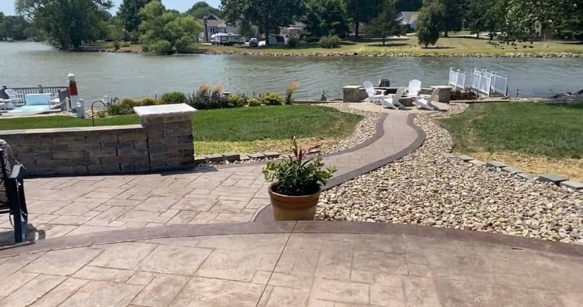 Lakeside patio with a stone seat wall and a curving walkway to the water