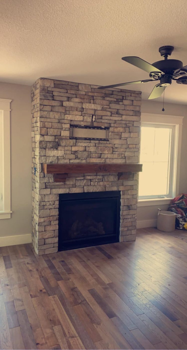 Floor-to-ceiling stacked ledgestone fireplace with a wood mantel