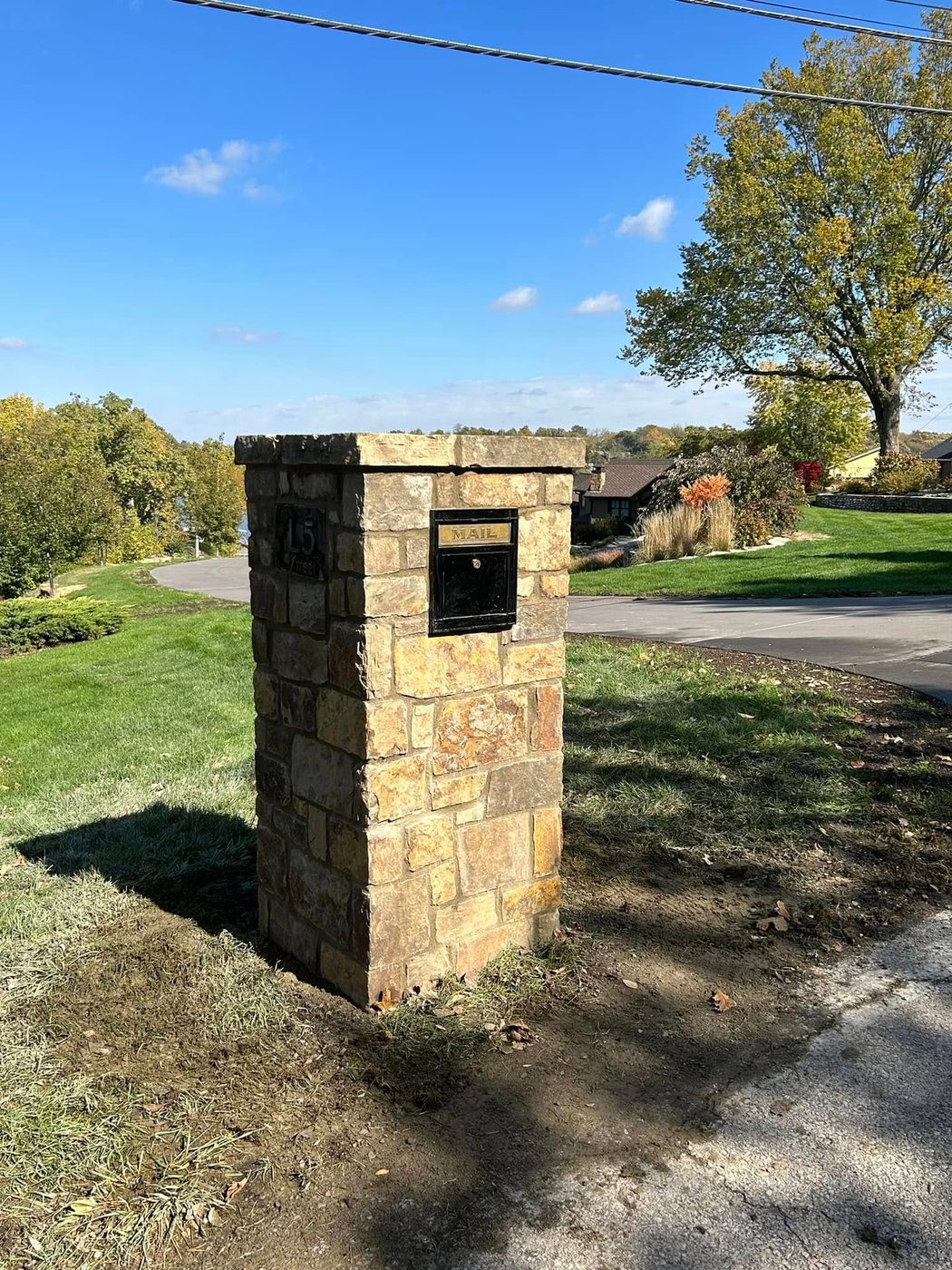 Tan stone mailbox column by a driveway