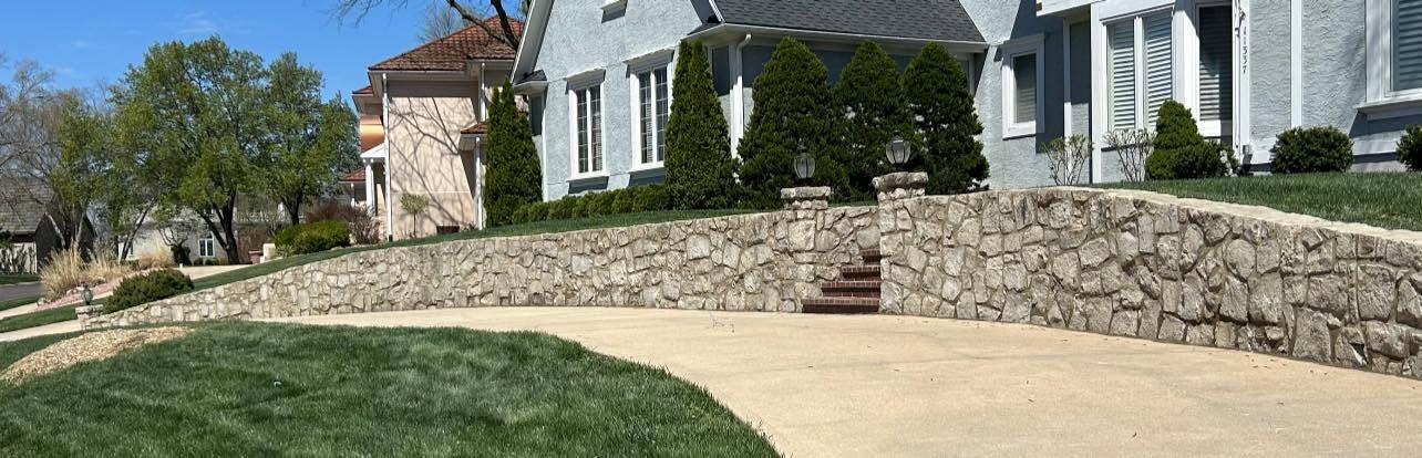 Long stone retaining wall with steps along a curved front lawn