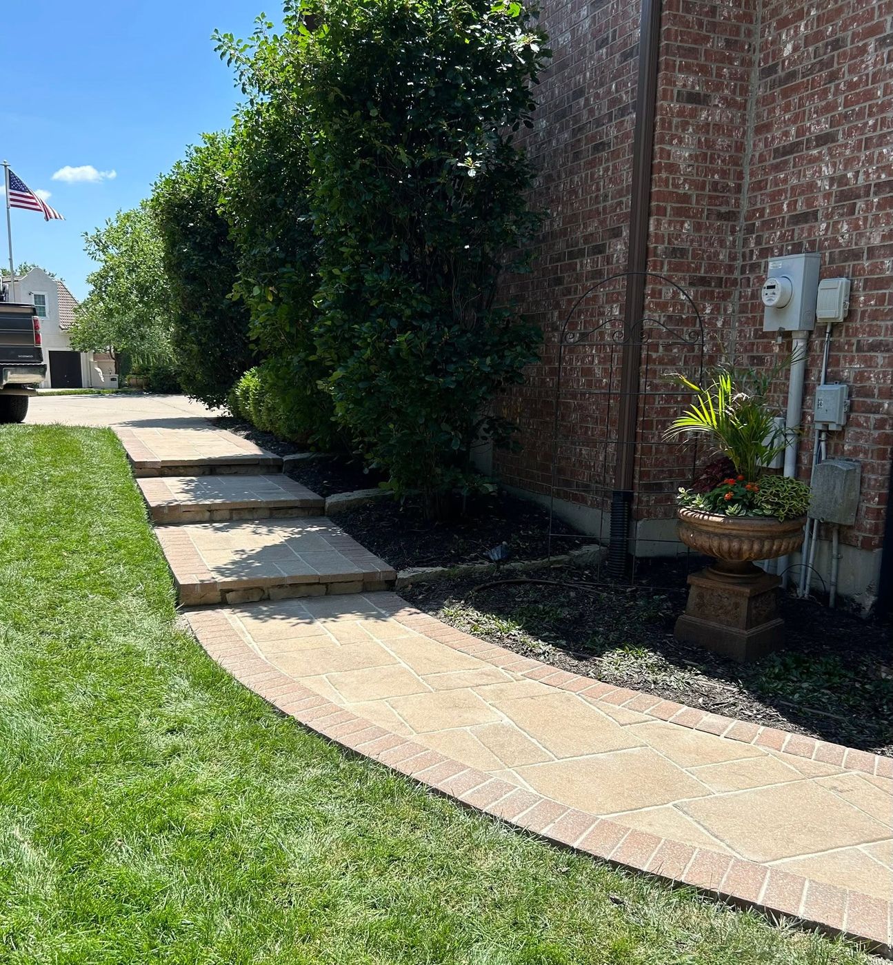 Curving paver sidewalk with a brick border along a brick house