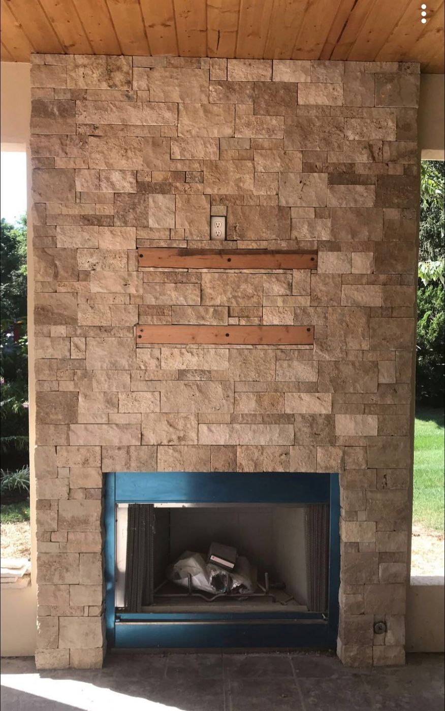 Covered porch fireplace in tan cut stone with wood mantel inlays
