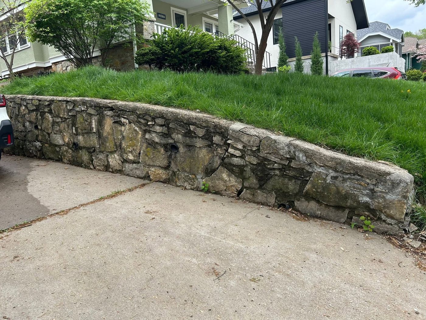 Weathered, mossy stone wall along a driveway