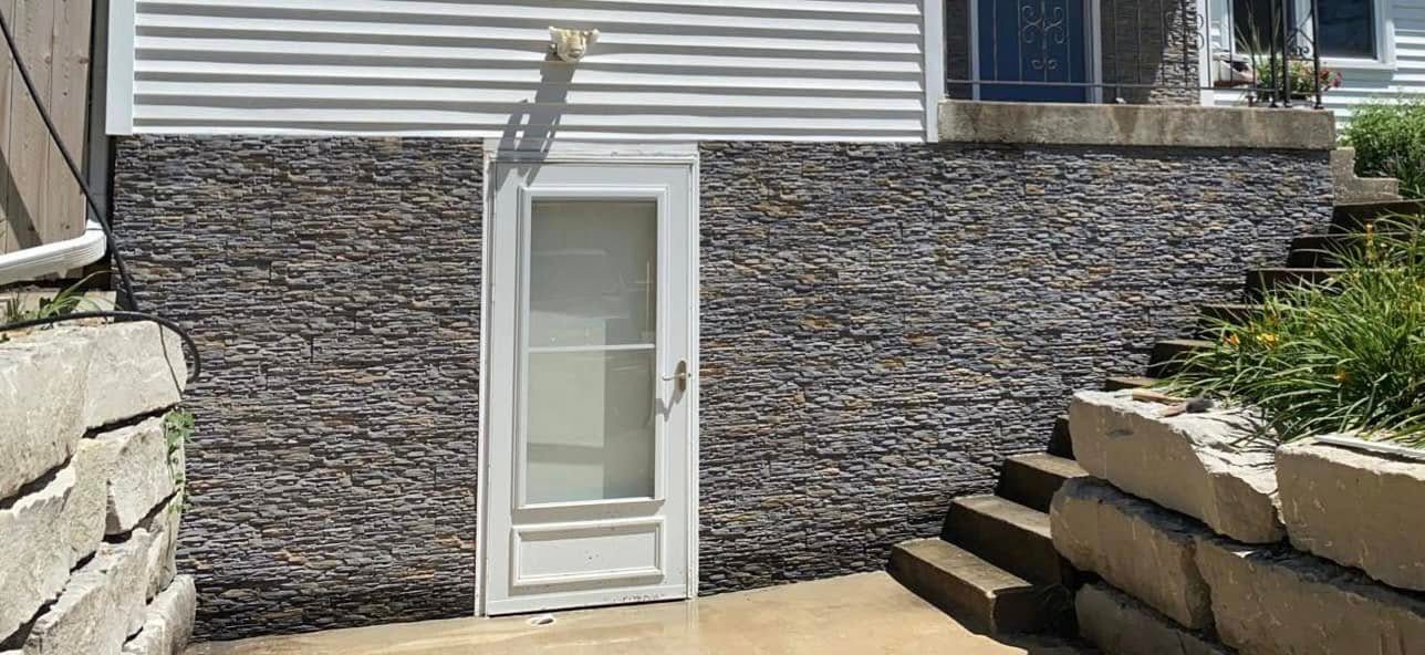 Lower house wall faced in slate ledgestone beside boulder steps