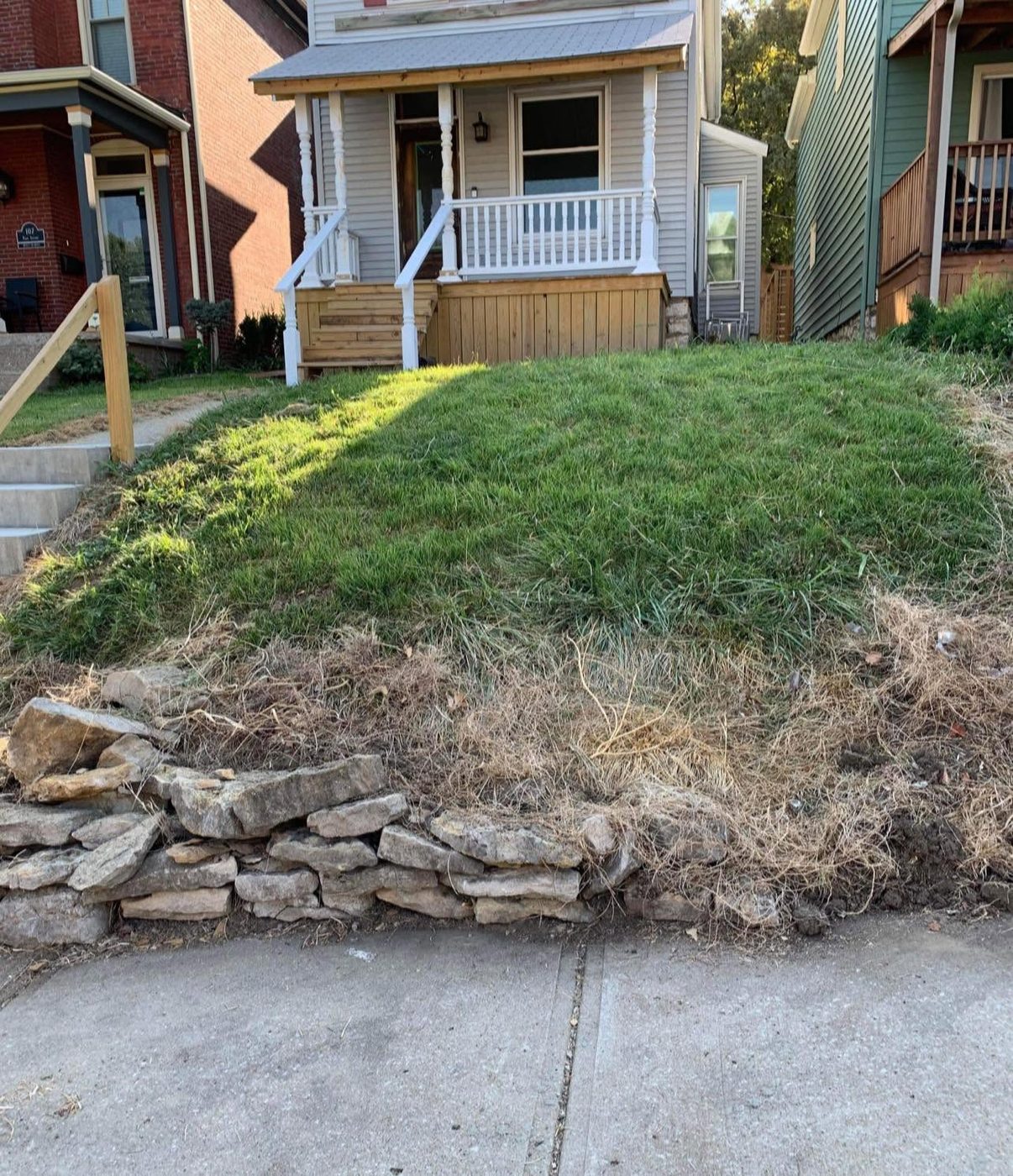 Loose stacked stones failing at the bottom of a front yard slope