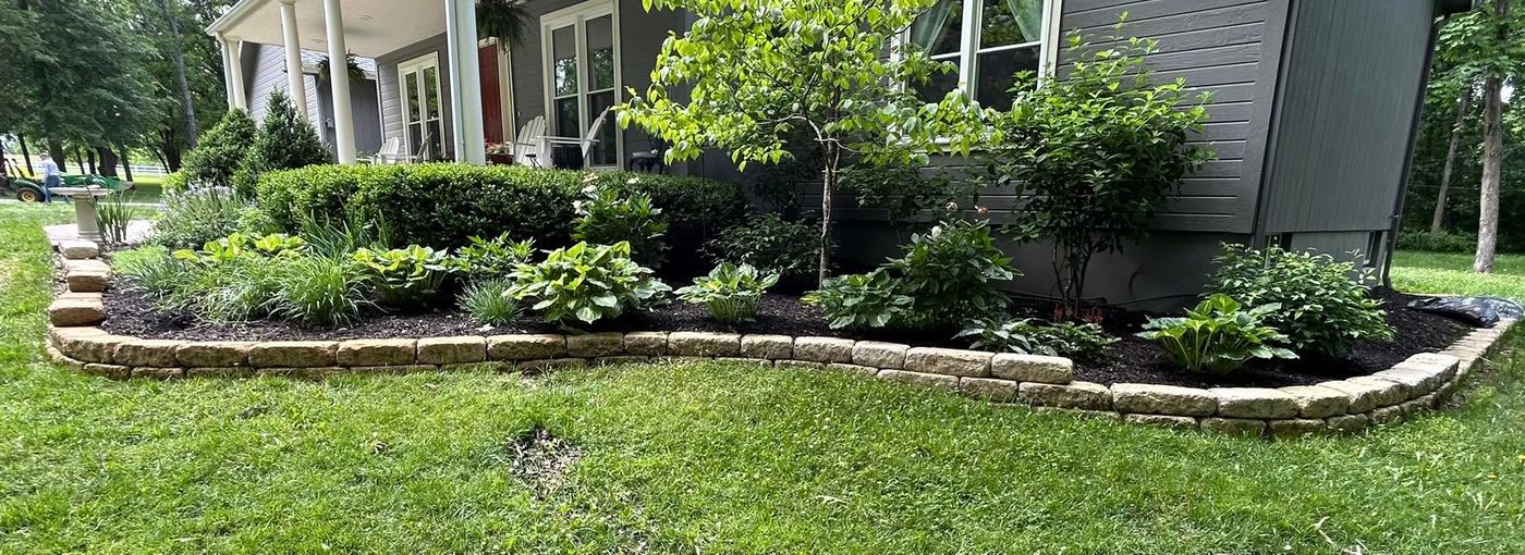 Low stone border wall around a front garden bed